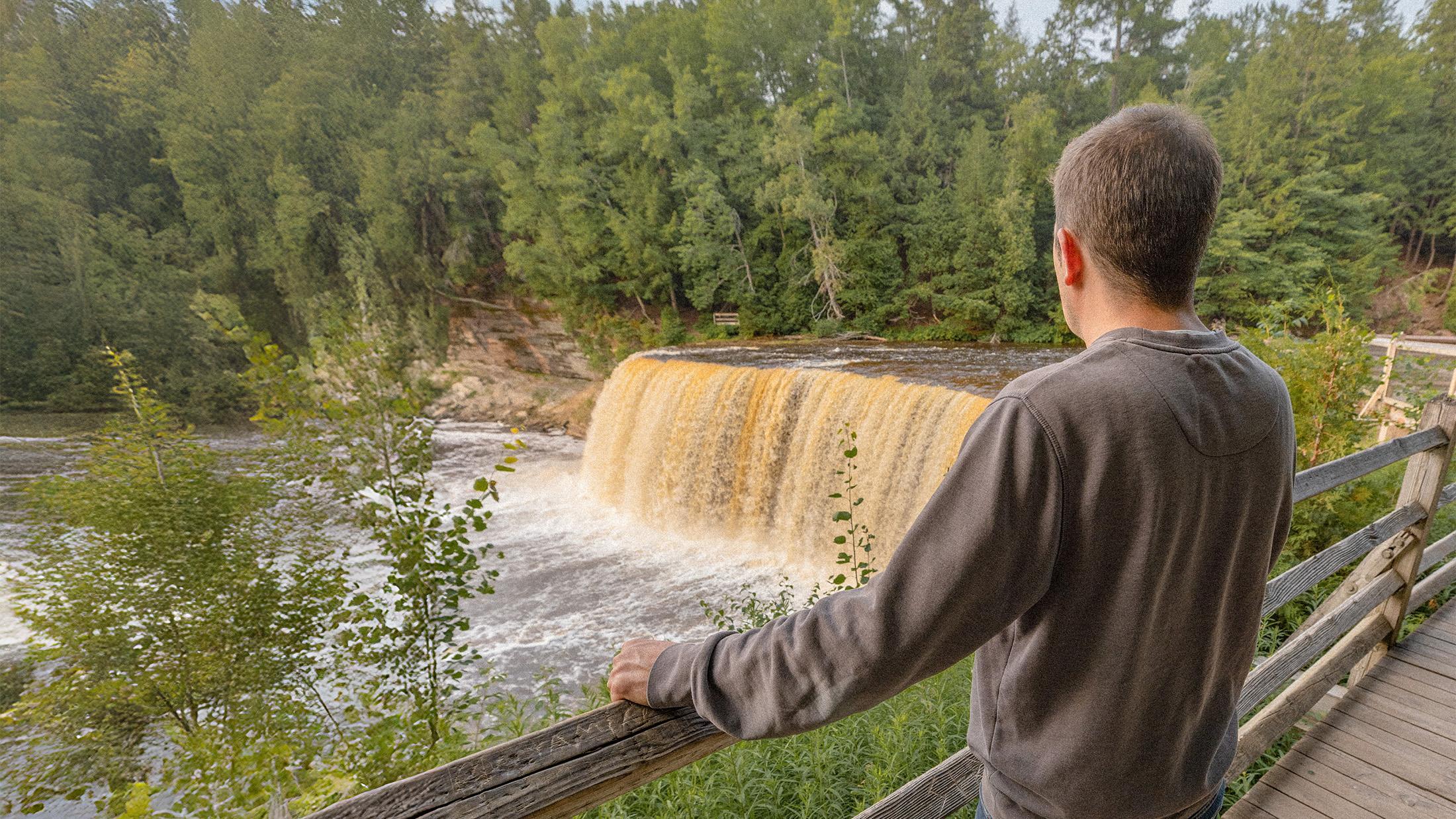 A person enjoying the view Tahquamenon Falls from the upper observation platform.